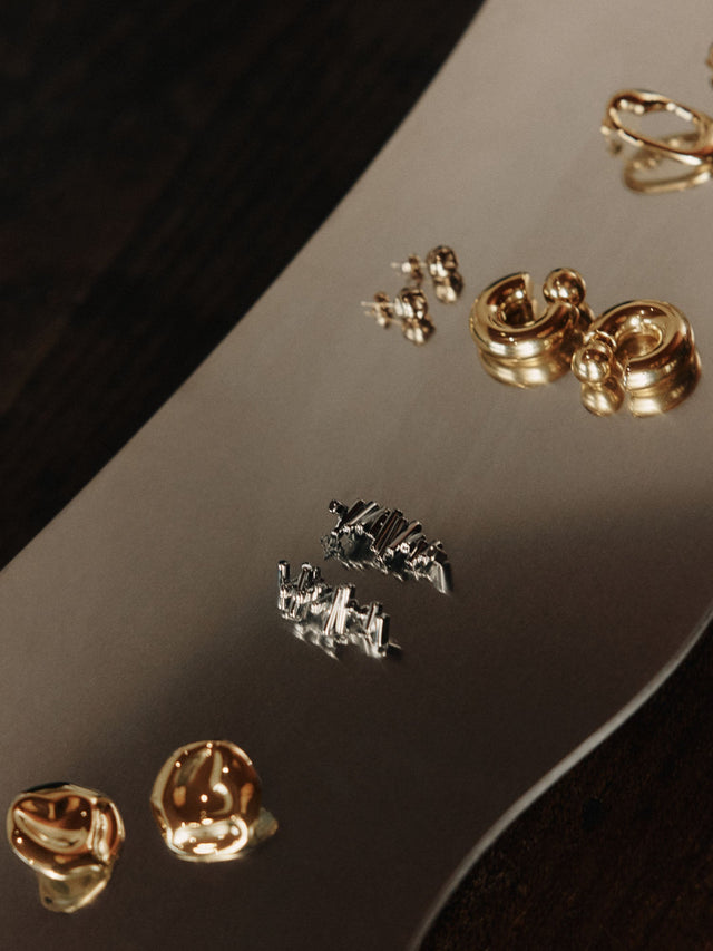 Goldene Ohrringe auf glänzendem Untergrund, elegant und modern – PURELEI.