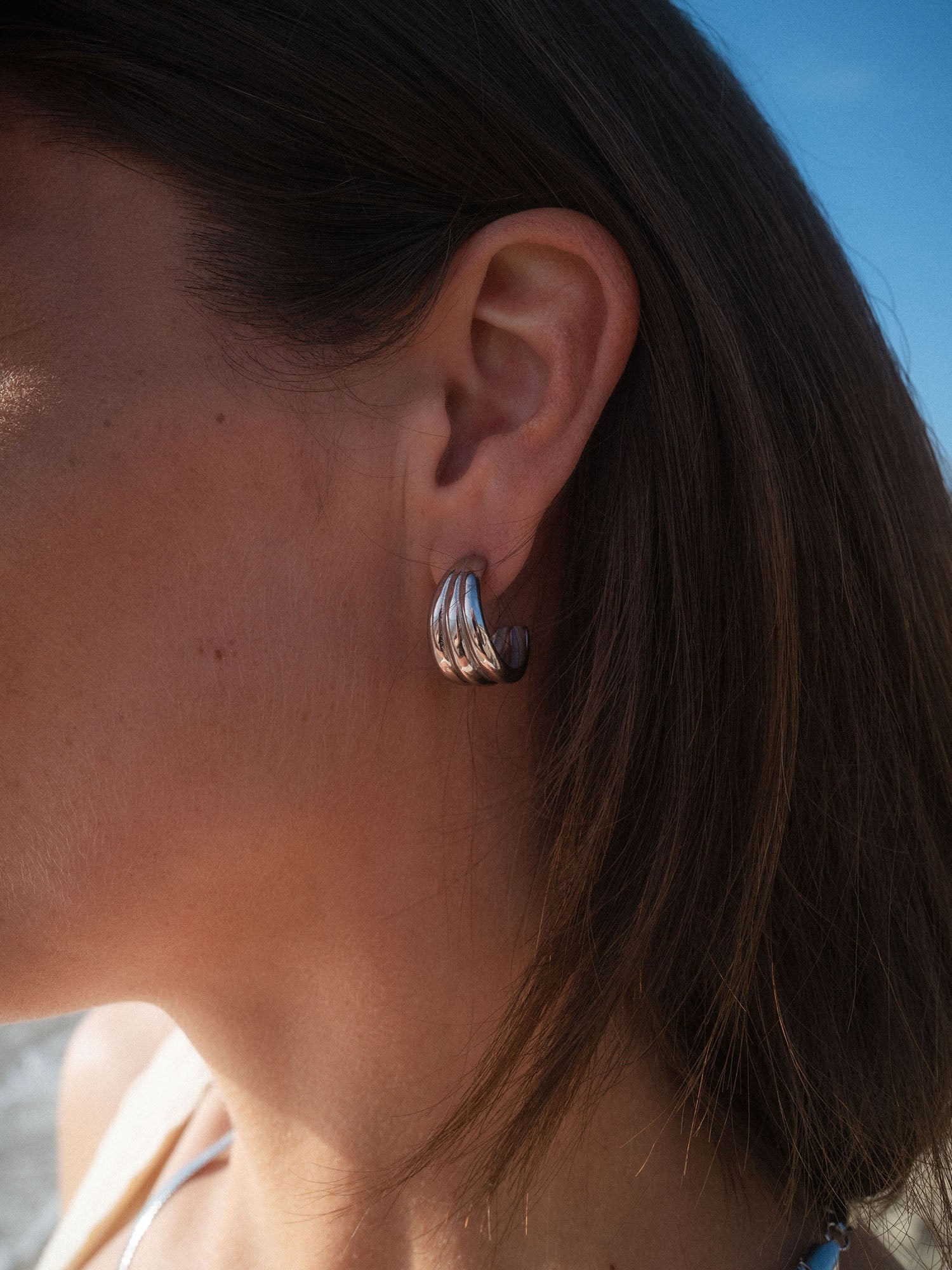 PURELEI Fused Ohrringe in Silber mit verschmolzenem Design, stilvoll und elegant am Ohr getragen.