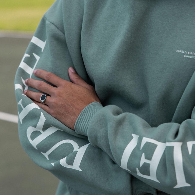 Locker sitzender PURELEI Wave Hoodie in Salbei mit weißem Schriftzug auf Armen und Brust, nachhaltig und bequem.